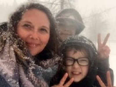 Jessie Anderson with 2 students showing peace signs